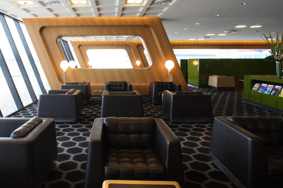 Leather armchairs facing the airfield windows in the Qantas Chairman's Lounge at Sydney Airport Terminal 3